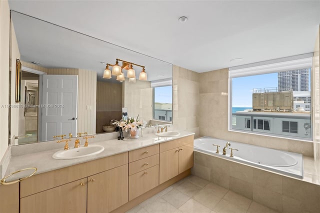 bathroom featuring tile patterned floors, tiled tub, vanity, and toilet