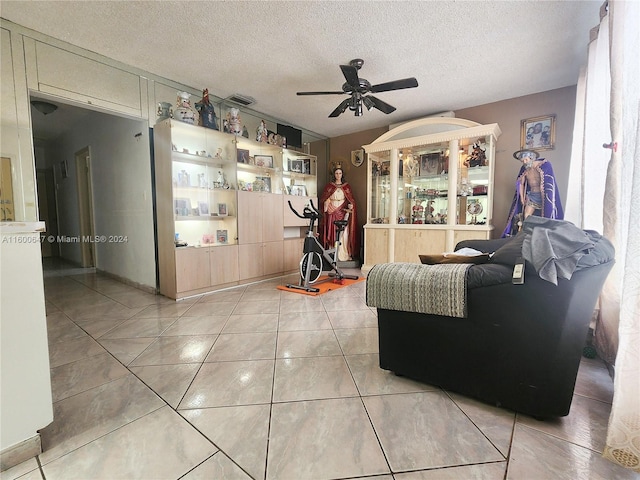 living room with a textured ceiling, ceiling fan, and light tile patterned flooring