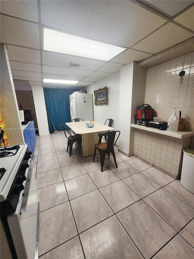 tiled dining area with a paneled ceiling