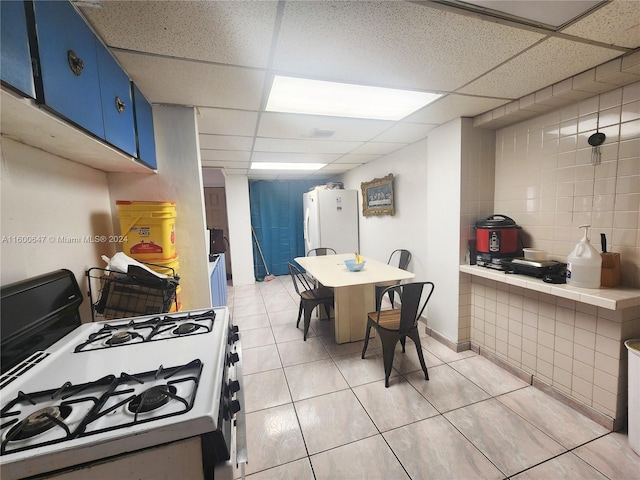 dining area with a paneled ceiling and light tile patterned floors