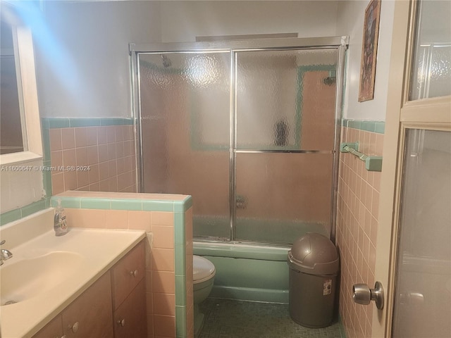 full bathroom with vanity, toilet, shower / bath combination with glass door, and tile walls