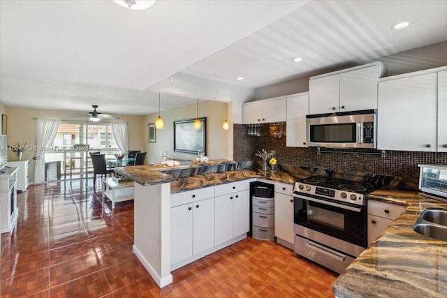 kitchen featuring white cabinets, appliances with stainless steel finishes, backsplash, and kitchen peninsula