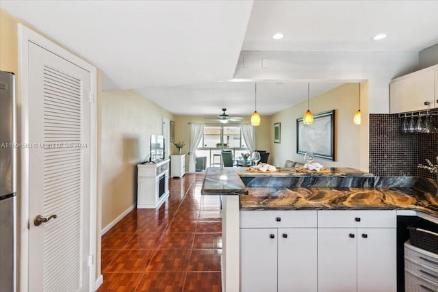 kitchen featuring white cabinetry, dark stone countertops, pendant lighting, ceiling fan, and dark tile floors