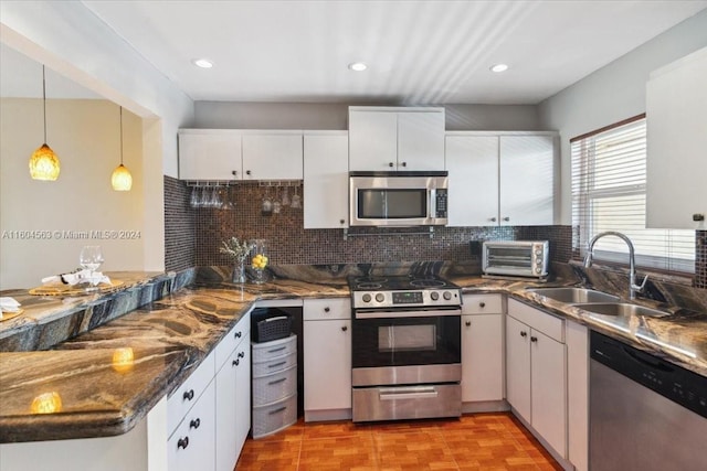 kitchen with stainless steel appliances, hanging light fixtures, tasteful backsplash, white cabinetry, and sink