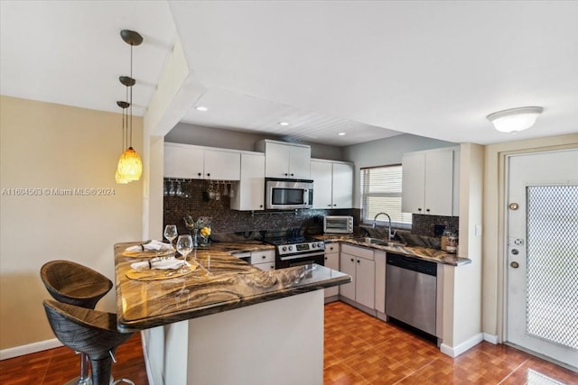 kitchen with kitchen peninsula, backsplash, light tile floors, white cabinets, and appliances with stainless steel finishes