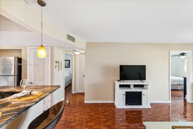 interior space with decorative light fixtures, stainless steel refrigerator, ceiling fan, and dark tile flooring