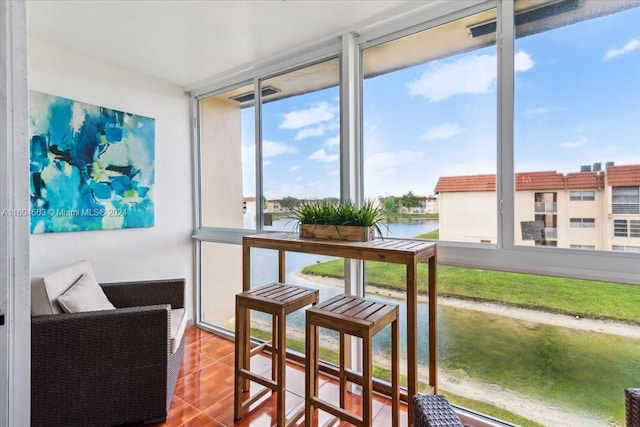 sunroom featuring a water view