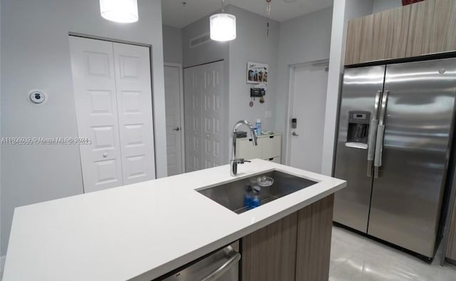 kitchen featuring sink, stainless steel refrigerator with ice dispenser, and pendant lighting