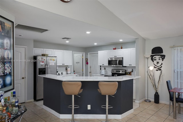 kitchen with white cabinets, appliances with stainless steel finishes, a center island with sink, and a kitchen breakfast bar