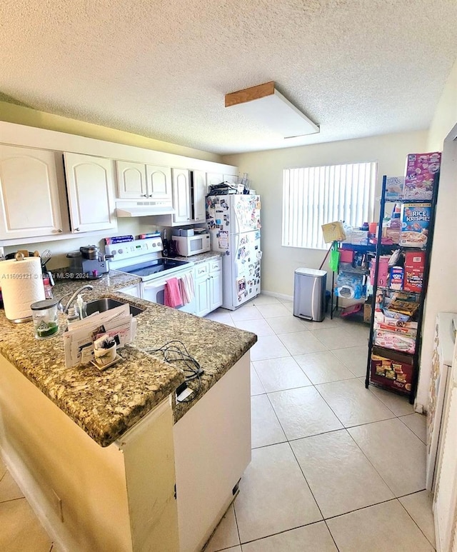 kitchen featuring white cabinets, white appliances, kitchen peninsula, and dark stone countertops