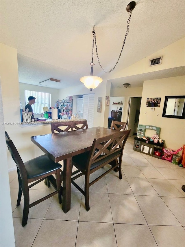 tiled dining space with lofted ceiling and a textured ceiling