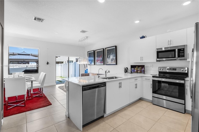 kitchen with stainless steel appliances, a peninsula, a sink, visible vents, and light countertops