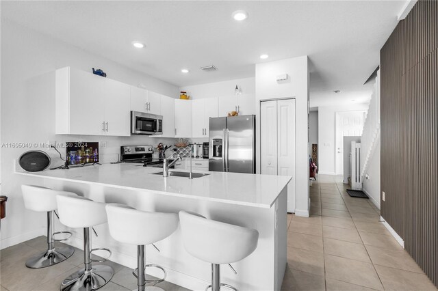 kitchen featuring white cabinets, appliances with stainless steel finishes, sink, and kitchen peninsula