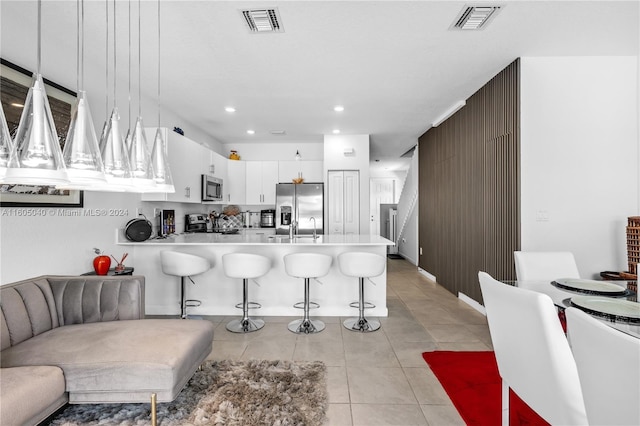 kitchen featuring stainless steel appliances, visible vents, a peninsula, and white cabinetry