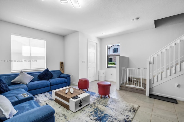 tiled living area featuring stairway, baseboards, and a textured ceiling