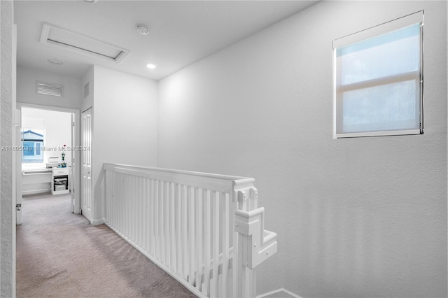 corridor with carpet floors, attic access, visible vents, and an upstairs landing