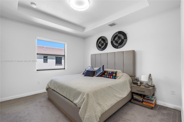 carpeted bedroom with baseboards, visible vents, and a raised ceiling