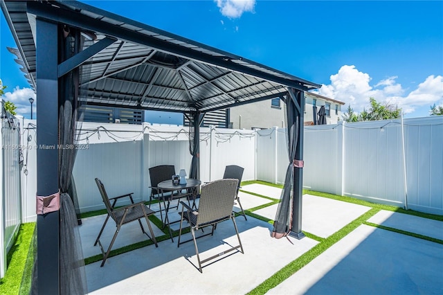 view of patio with a gazebo, outdoor dining space, and a fenced backyard