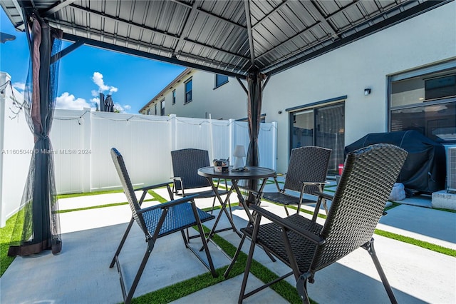 view of patio with outdoor dining area, fence, and a gazebo