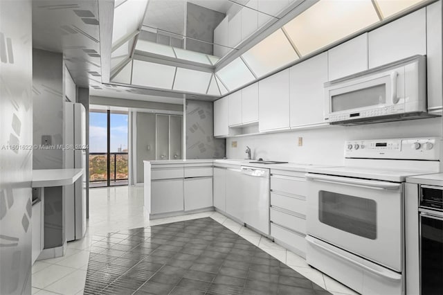 kitchen with sink, white appliances, white cabinetry, and light tile floors