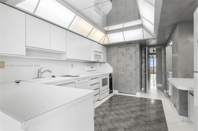 kitchen with white appliances, white cabinets, kitchen peninsula, sink, and light tile floors