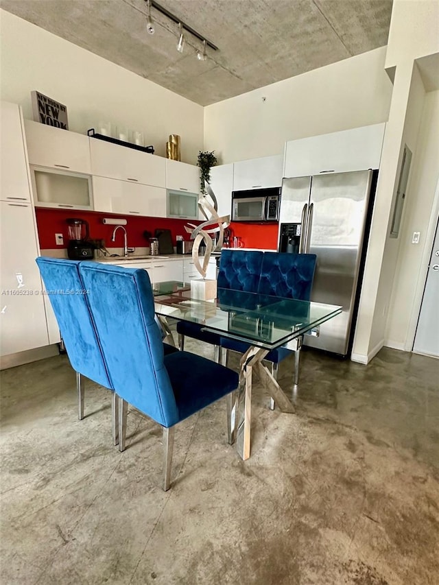 dining room with track lighting and concrete flooring