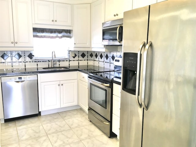 kitchen featuring white cabinets, backsplash, appliances with stainless steel finishes, and sink