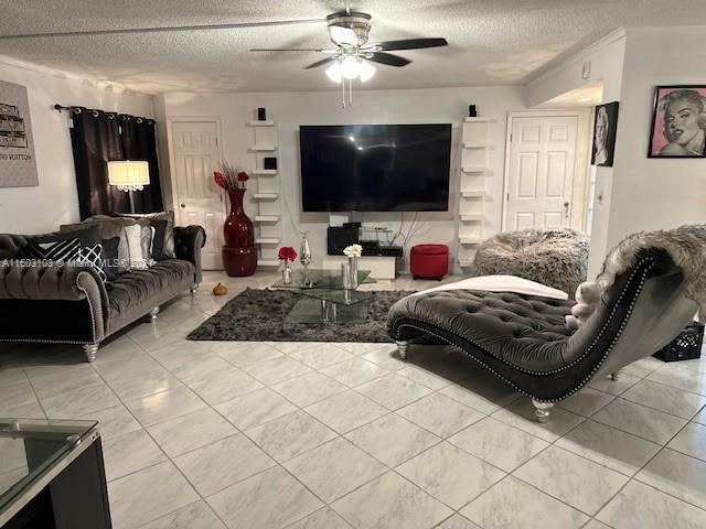 tiled living room featuring ceiling fan and a textured ceiling