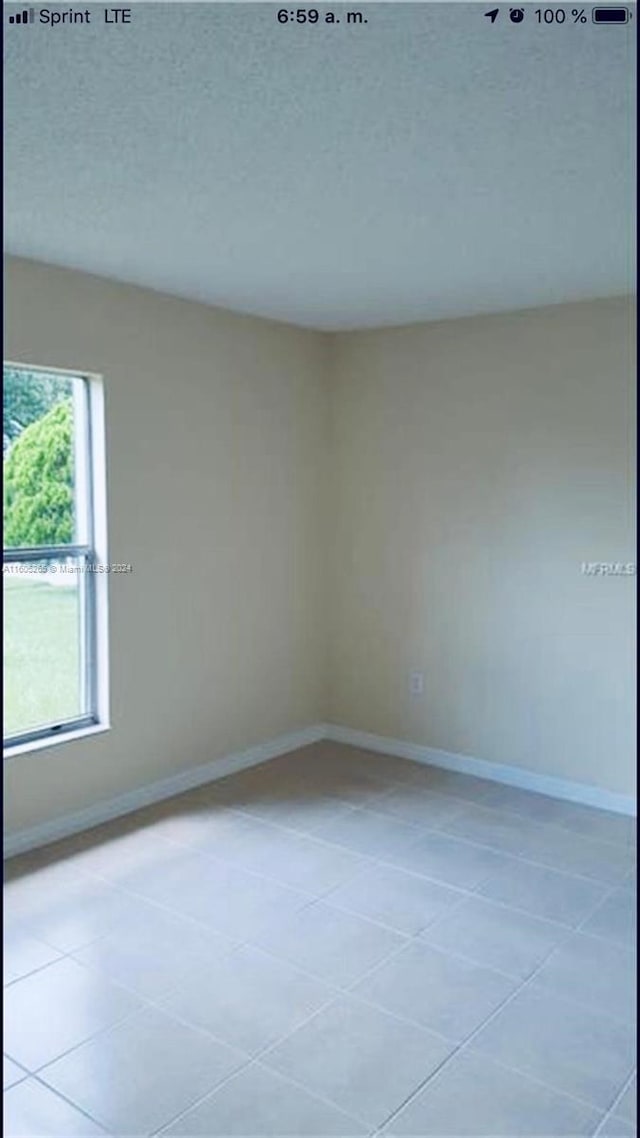 tiled empty room with a textured ceiling