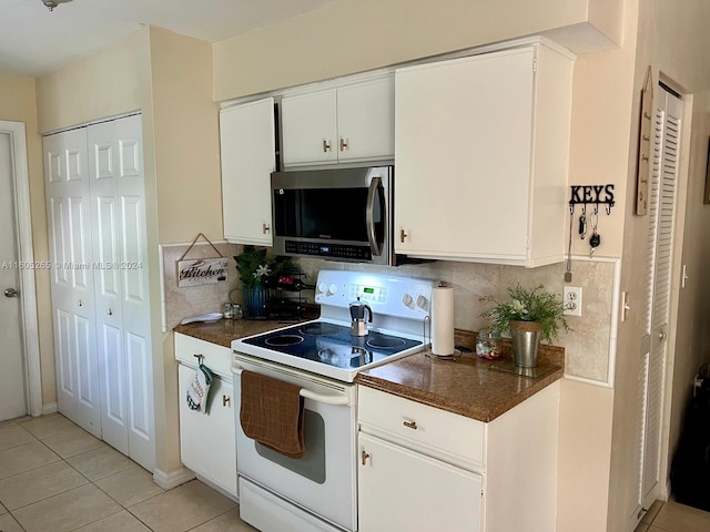 kitchen featuring white electric range, white cabinets, tasteful backsplash, and light tile floors