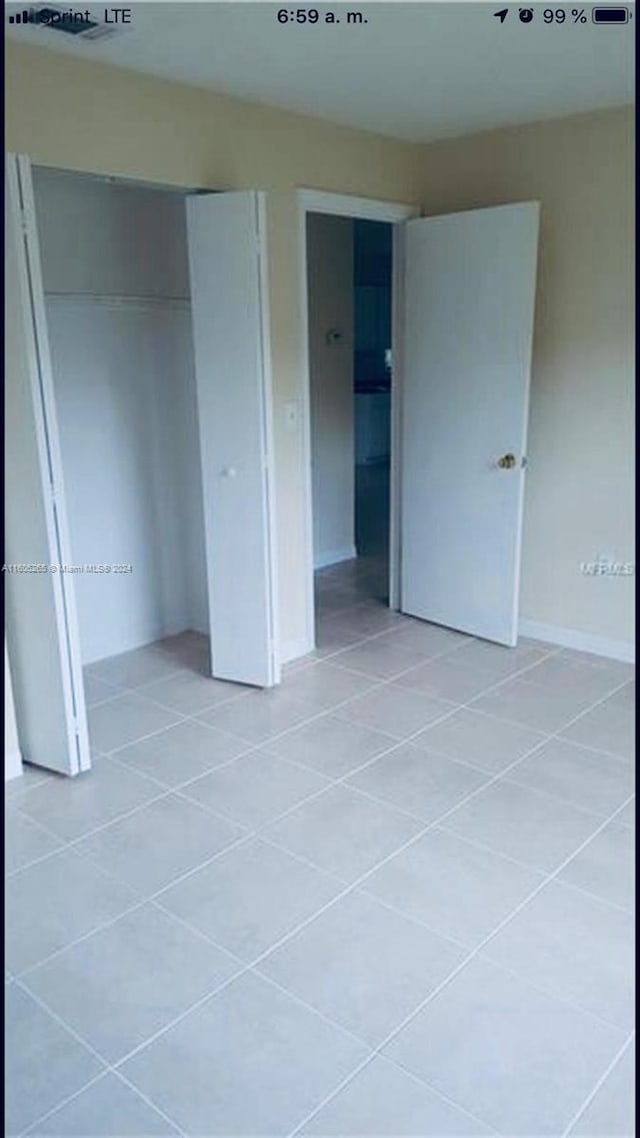 unfurnished bedroom featuring a closet and light tile floors