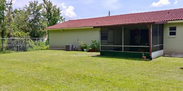 rear view of house with a yard, a sunroom, and central AC unit