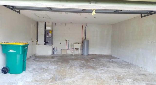 garage with water heater, sink, and heating utilities