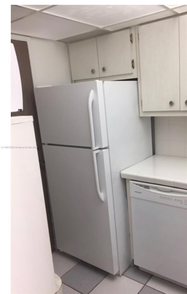 kitchen with white appliances, white cabinets, and light tile floors