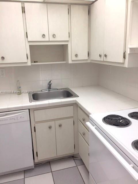 kitchen featuring light tile patterned flooring, sink, white cabinetry, white appliances, and backsplash