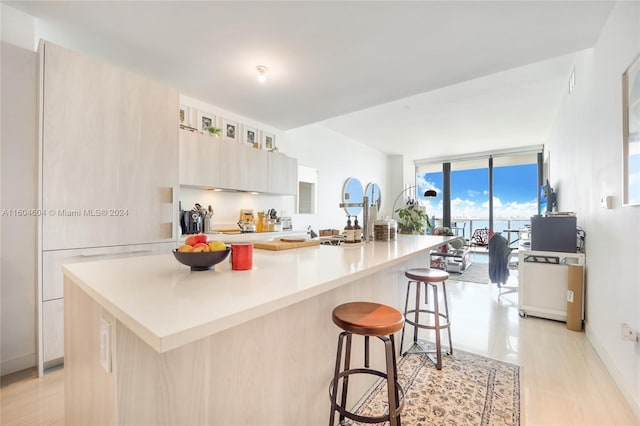 kitchen featuring expansive windows, a center island with sink, and a kitchen bar