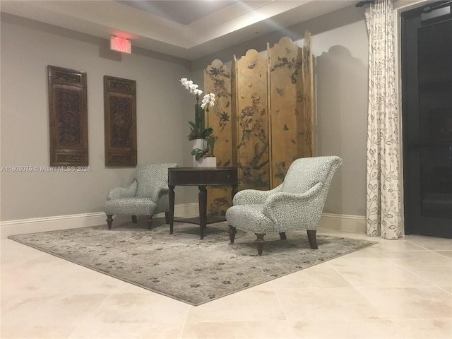 living area with tile flooring and a raised ceiling