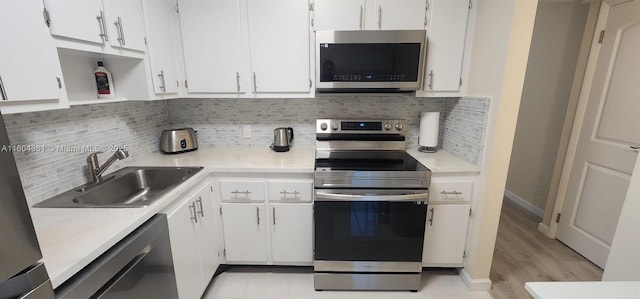 kitchen featuring a sink, white cabinets, light countertops, appliances with stainless steel finishes, and decorative backsplash