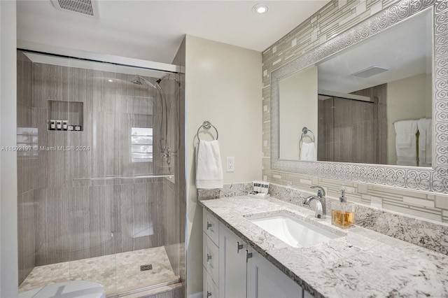 bathroom with backsplash, vanity, a shower with shower door, and toilet