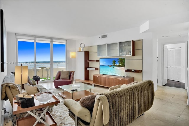 living room with a water view, a wall of windows, and light tile floors