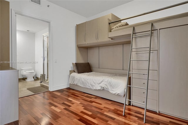 unfurnished bedroom with ensuite bathroom and light wood-type flooring