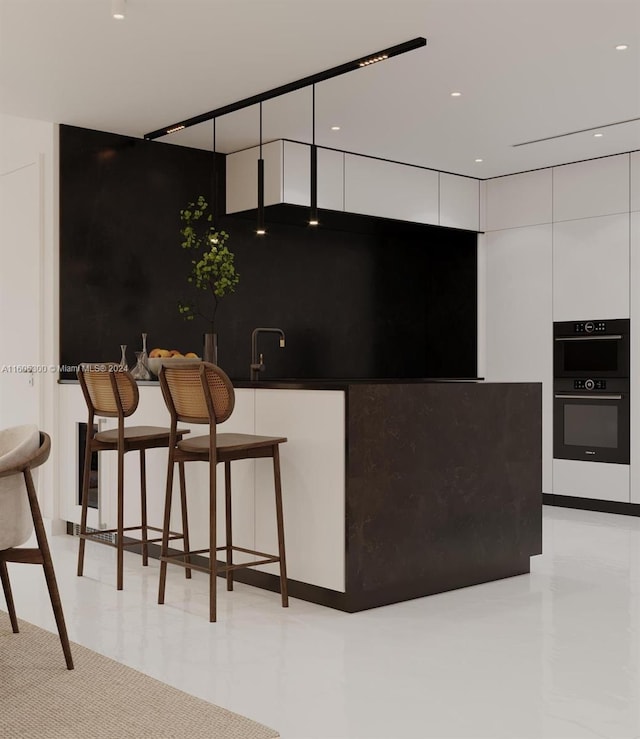 kitchen with white cabinetry, black double oven, and a breakfast bar