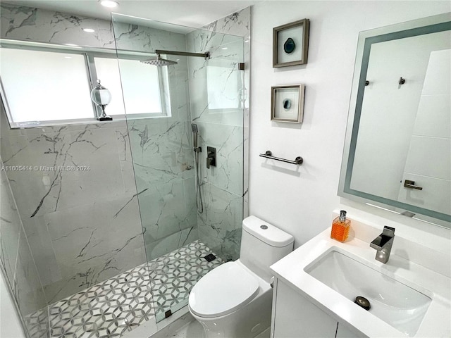 bathroom featuring vanity, toilet, a wealth of natural light, and a shower with shower door