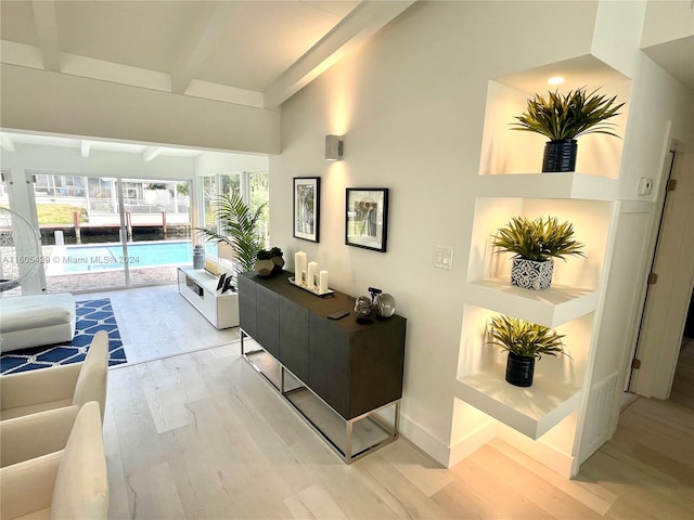 living room featuring beamed ceiling, a towering ceiling, and light wood-type flooring