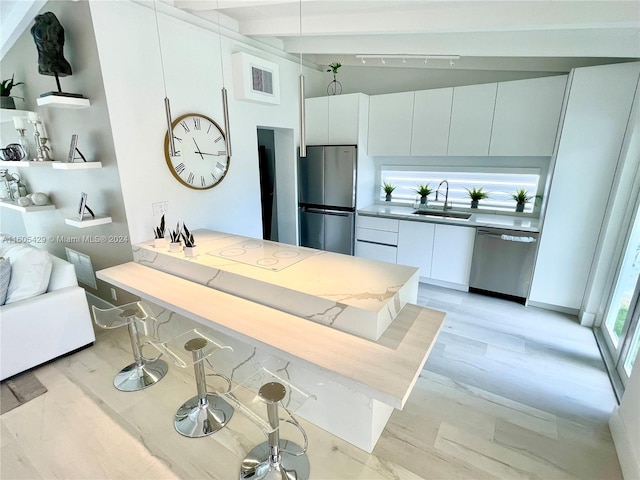 kitchen featuring stainless steel appliances, a kitchen bar, light wood-type flooring, beamed ceiling, and white cabinets