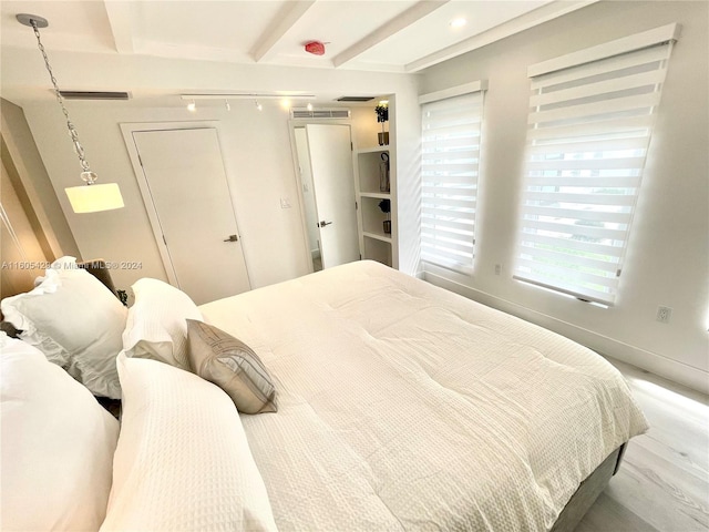 bedroom featuring beam ceiling, a closet, and hardwood / wood-style flooring