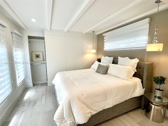 bedroom featuring beamed ceiling, multiple windows, and light hardwood / wood-style flooring