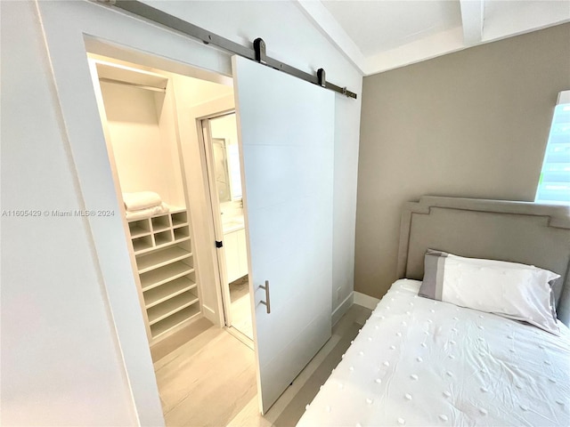 bedroom with hardwood / wood-style floors, a walk in closet, a barn door, and a closet