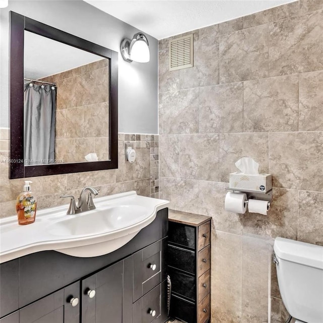 bathroom with vanity, a shower with shower curtain, tile walls, and toilet