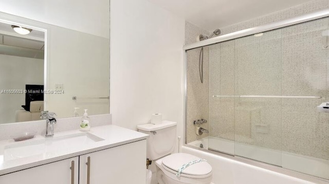 full bathroom with combined bath / shower with glass door, vanity, and toilet